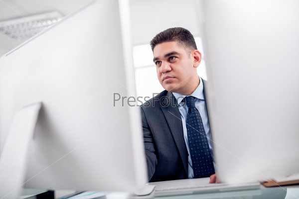 Serious businessman reading information on the computer screen