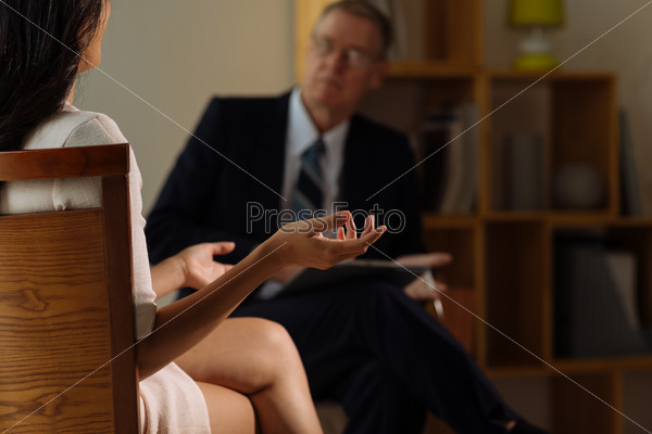 Female patient talking to psychologist, rear view