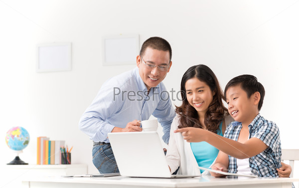Cheerful Asian family watching something on laptop