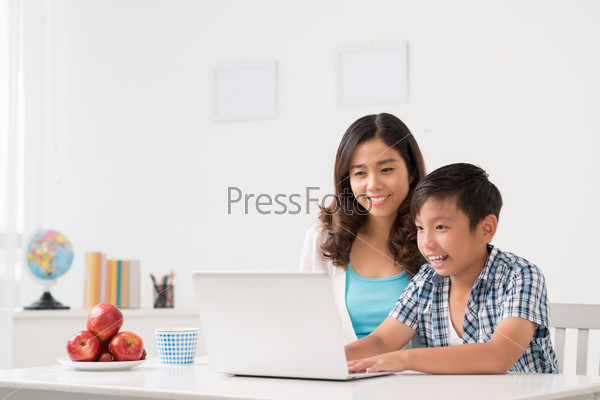 Cheerful boy showing his mother something on the laptop