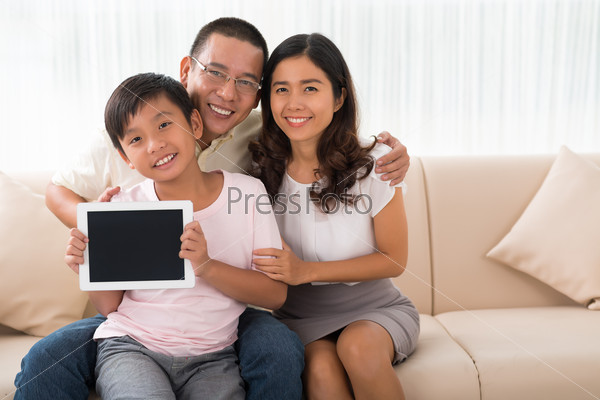 Happy smiling Vietnamese family with a digital tablet sitting on a couch