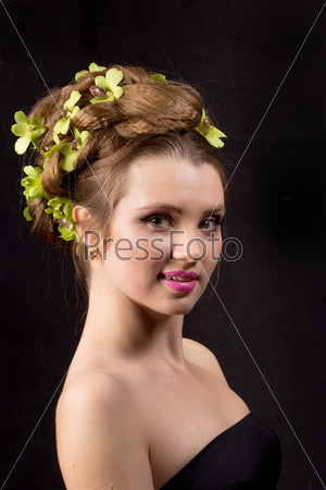 Beautiful woman with orchid flower in hair posing on black background