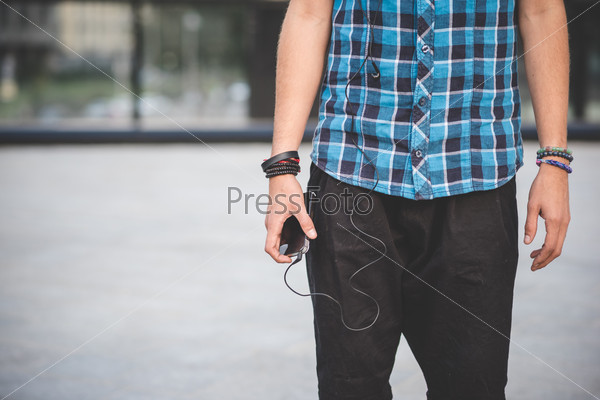 close up of hands guy with smartphone and earphones in the city