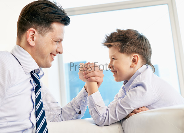 Young man and his son armwrestling