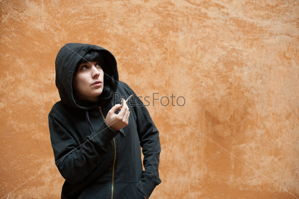 Dark young woman sad standing and smoking near urban wall portra