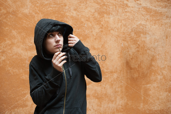 Dark young woman sad standing and smoking near urban wall portrait