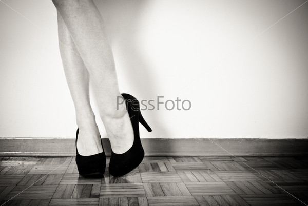 young sexy woman feet with black high heels and legs, close up in black and white