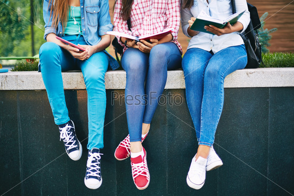 Modern teen girls reading outside