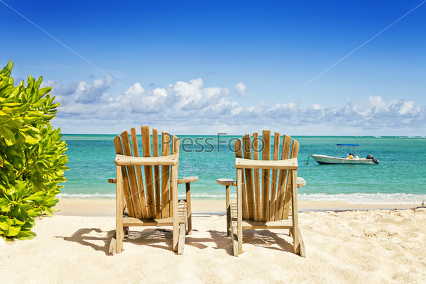 Two beach chairs on tropical shore, horizontal composition