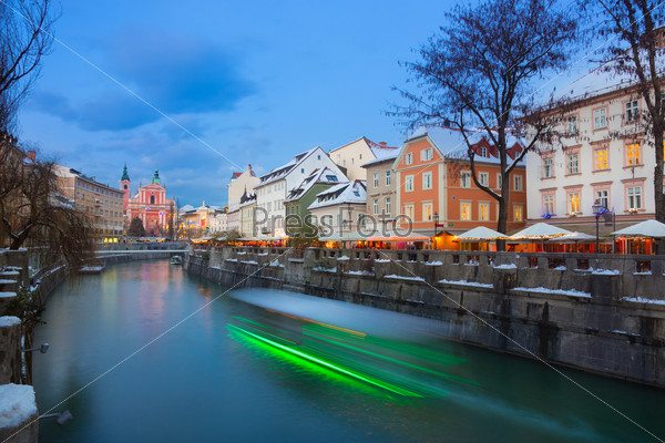 View of lively river Ljubljanica bank and Tromostovje in old city center decorated with Christmas lights at dusk. Ljubljana, Slovenia, Europe.