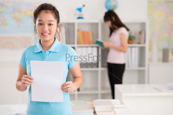 Cheerful Vietnamese schoolgirl holding blank sheet of paper
