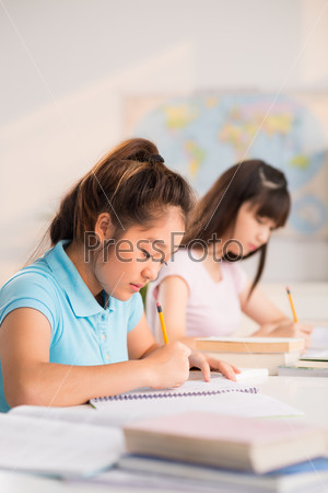 Concentrated students writing exercises in notebooks