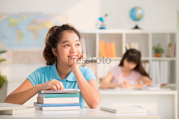Portrait of dreamy Vietnamese schoolgirl sitting in the class