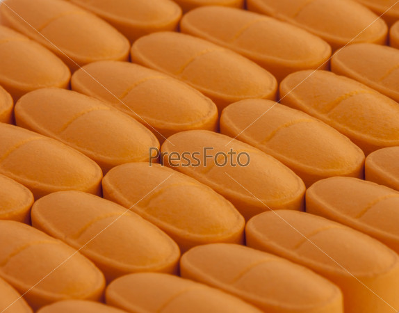 bunch of orange vitamin pills spilled on the table
