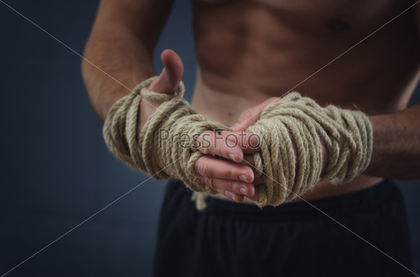 Close-up of a young Thai boxer hands hemp ropes are wrapped before the fight or training.