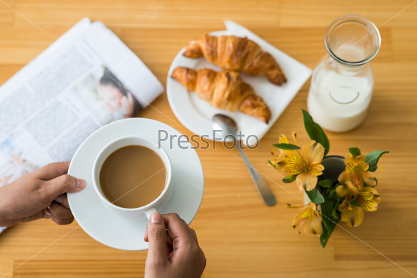 Hands with coffee cup above the breakfast table