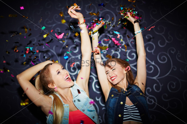 Two energetic girls dancing in night club