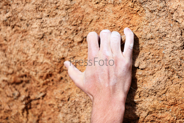 Climbing hand closeup grip during rock climbing. Male hand with chalk powder on rocks.
