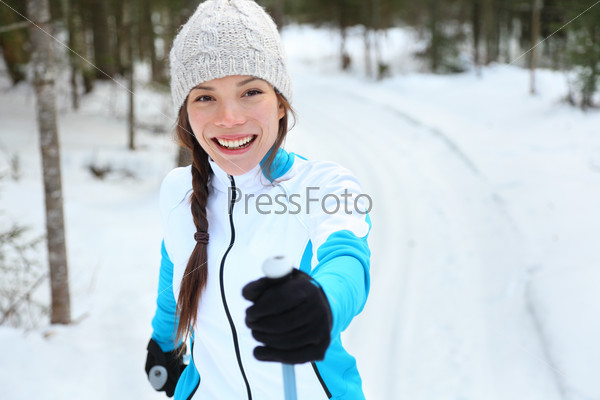 Cross-country skiing woman doing classic nordic cross country skiing in trail tracks in snow covered forest in Quebec, Canada