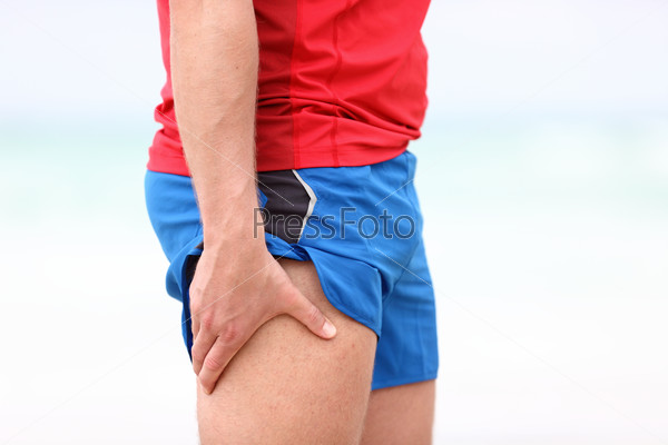 Sports injury. Running muscle stain injury in thigh. Closeup of runner touching leg in muscle pain.