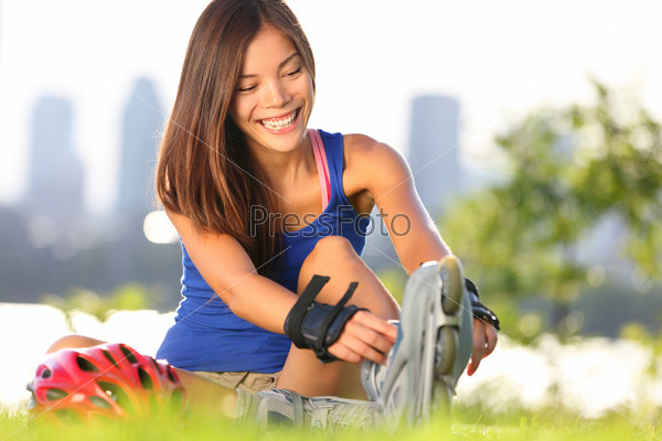 Roller skating woman putting on inline skates for\
rollerblading. Healthy outdoor workout woman skating outside with\
montreal city skyline in background.