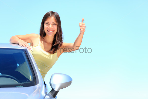Car Woman driver happy smiling showing thumbs up coming out\
of car window on blue summer sky above the clouds Beautiful young\
mixed race Caucasian Chinese Asian woman