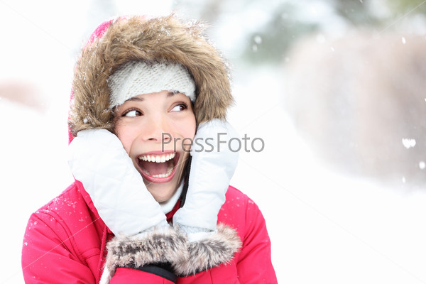 Excited winter woman looking to side smiling happy and joyful holding head. Beautiful mixed race asian caucasian girl playful in the snow.