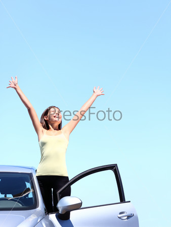 Car woman happy freedom concept. Cheering young woman with arms raised stepping out of new car under blue sky. Beautiful young multiracial Asian / Caucasian female model free.