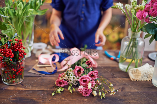 Bunch of flowers with pink ribbon with designer hands over it
