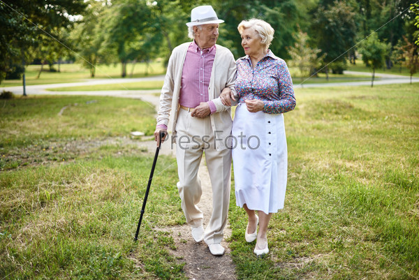 Portrait of well-dressed seniors walking in summer