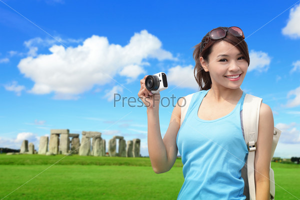Happy woman traveler in Stonehenge, an ancient prehistoric stone monument , UK. in England,  asian girl