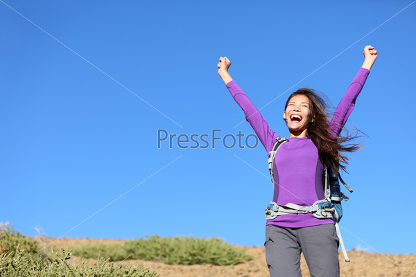 success woman happy outside on adventure cheering with arms in the air screaming cheerful with winning attitude while hiking. Beautiful young mixed race Caucasian Asian female hiker.
