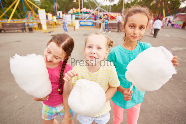 Cute girls eating cotton candy outdoors