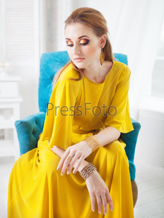 Portrait of young beautiful girl with make up wearing long yellow dress
