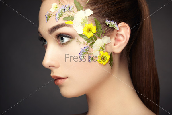 Face of beautiful woman decorated with flowers. Perfect makeup. Beauty fashion. Eyelashes. Cosmetic Eyeshadow, stock photo
