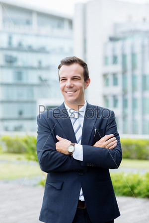 Portrait of laughing businessman standing with his arms crossed