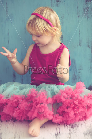 Portrait of cute little princess wearing beautiful tutu skirt on vintage wooden background