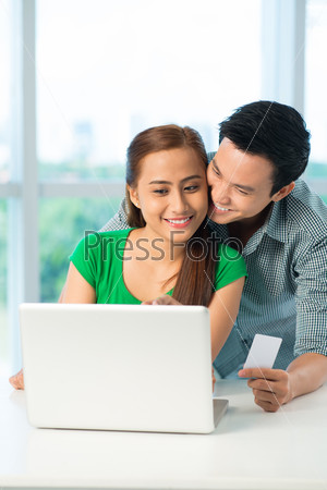 Happy Vietnamese couple using laptop to shop online