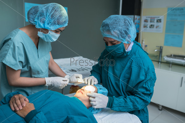Surgeon and assistant applying medical match on eye of patient