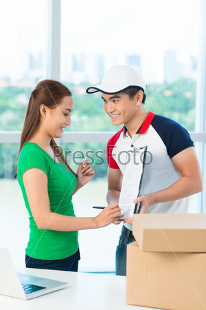 Smiling Asian woman signing for receiving packages