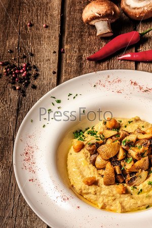 corn porridge with pumpkin  with mushrooms on white plate and wooden background