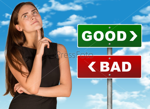 Thoughtful businesswoman standing near colorful good and bad signboard and looking up on blue sky background