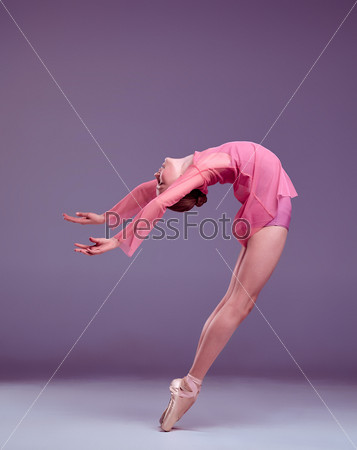 Young ballerina dancer in pink dress showing her techniques on lilac background