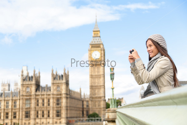 Travel tourist in london sightseeing taking photo pictures near Big Ben. Woman holding smart phone camera smiling happy near Palace of Westminster, Westminster Bridge, London, England