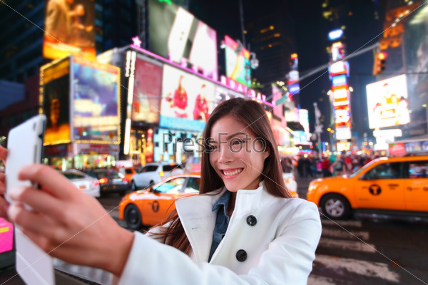 Happy woman tourist taking photo picture with tablet in New York City, Manhattan, Times Square. Girl traveler taking selfie joyful and happy smiling. Multiethnic Asian Caucasian woman in her 20s.