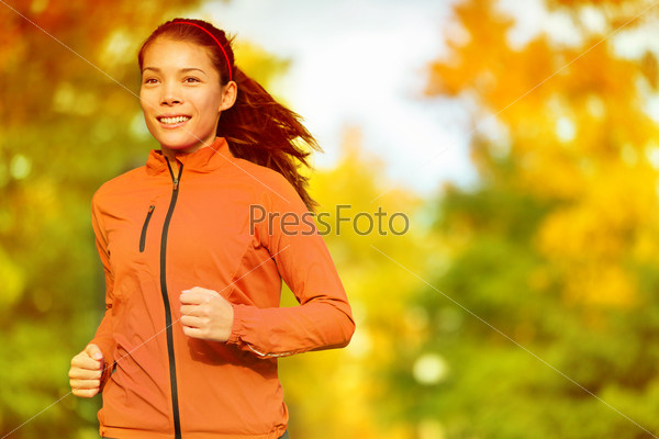 Runner woman running in fall autumn forest. Female fitness girl jogging on path in amazing fall foliage landscape nature outside.