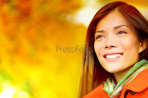 Autumn / Fall woman in colorful foliage in city park forest smiling happy. Portrait of modern girl and colorful leaves outdoor in fall forest foliage. Mixed race Asian Caucasian female model.