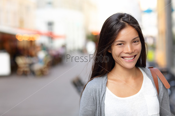 Asian woman candid portrait from street in Copenhagen city, Denmark. Young urban female smiling looking at camera.