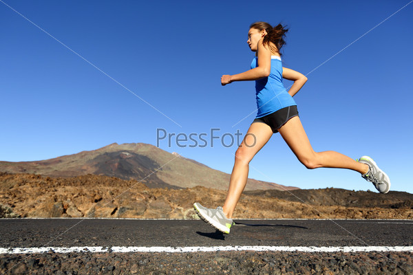 Sprinting running woman - female runner training outdoors jogging on mountain road in amazing landscape nature. Fit beautiful fitness model working out for marathon outside in summer.
