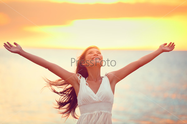 Free happy woman arms up praising freedom at beach sunset. Young adult enjoying breathing freely fresh air.